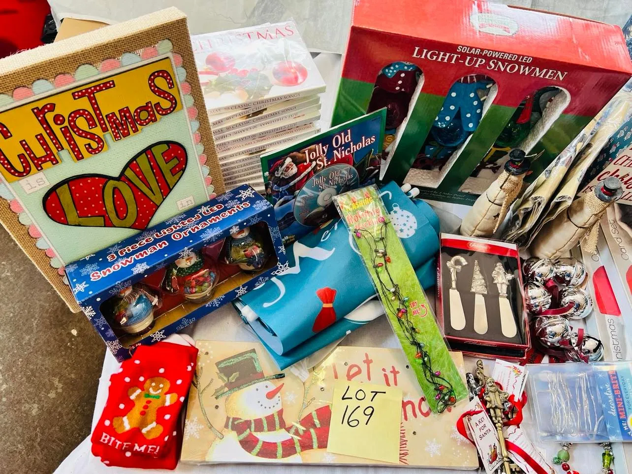 Lot 169- Large Lot Christmas New, 4 Christmas ugly sweaters, Artwork, Banners, outside 7 foot banners, 2 sets of Christmas Kitten cards, 17 Christmas CD sets, snowmen, solar stake, believe bells etc, 56 Pieces