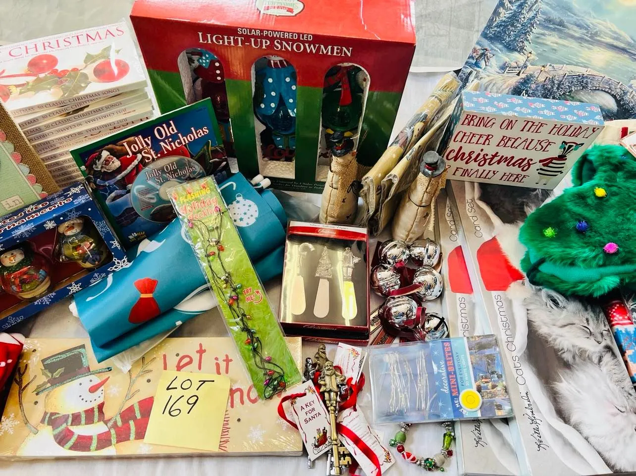 Lot 169- Large Lot Christmas New, 4 Christmas ugly sweaters, Artwork, Banners, outside 7 foot banners, 2 sets of Christmas Kitten cards, 17 Christmas CD sets, snowmen, solar stake, believe bells etc, 56 Pieces